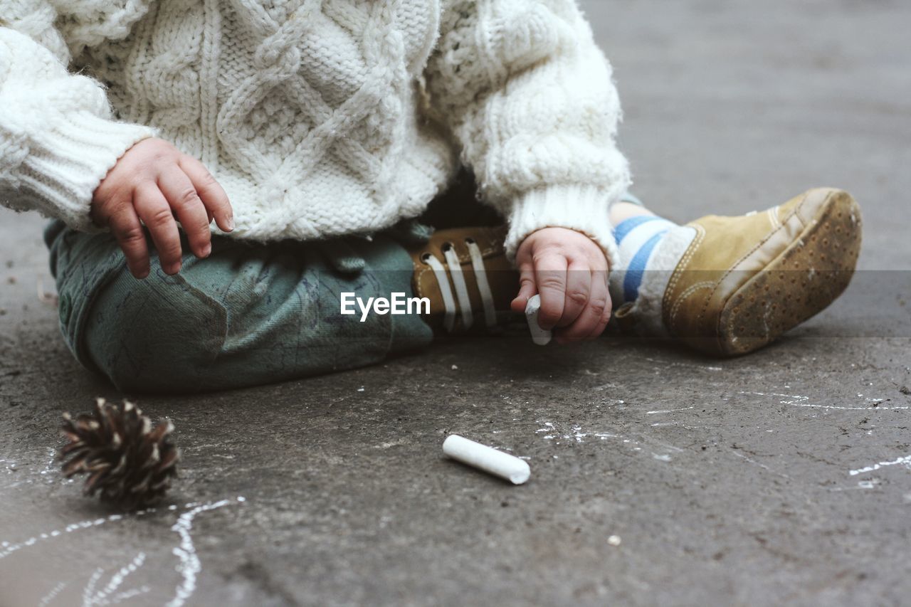 Close-up low section of baby sitting on ground