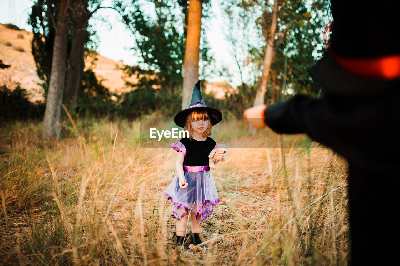 Girl with brother wearing costume during halloween at forest