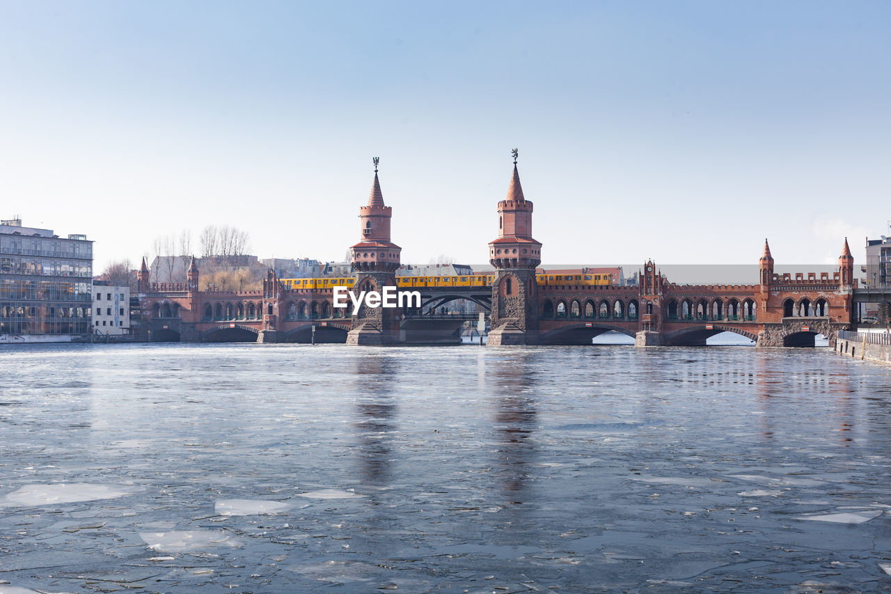 View of bridge over river against clear sky in city during sunny day