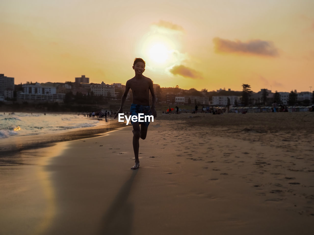 Silhouette of a happy asian boy running at the beach with a beautiful orange sunset 