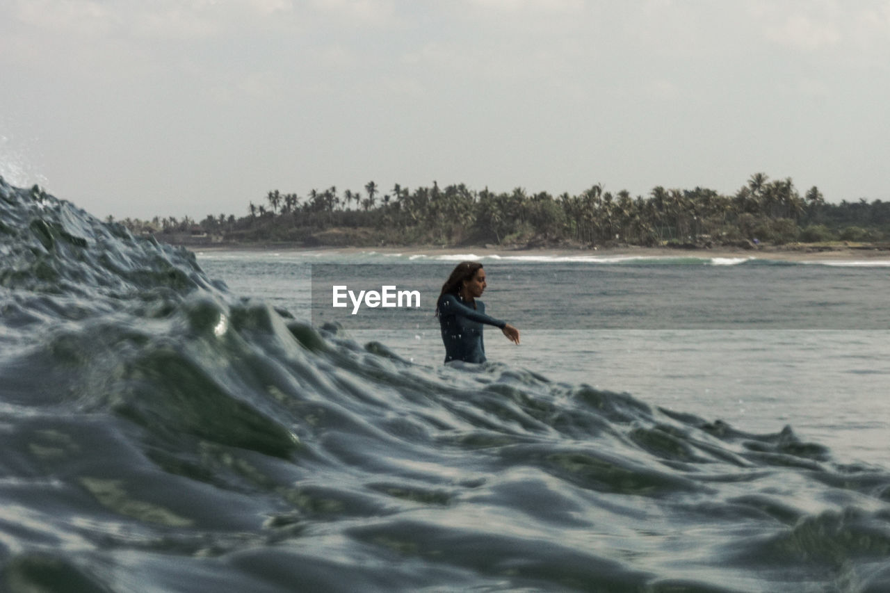 Woman in sea against sky