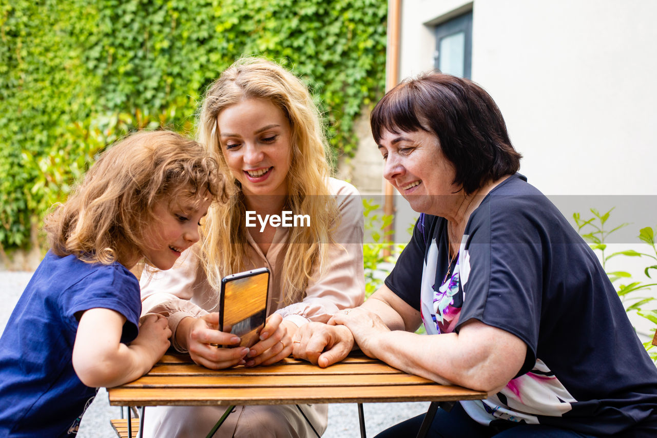 Women looking at camera while sitting on mobile phone