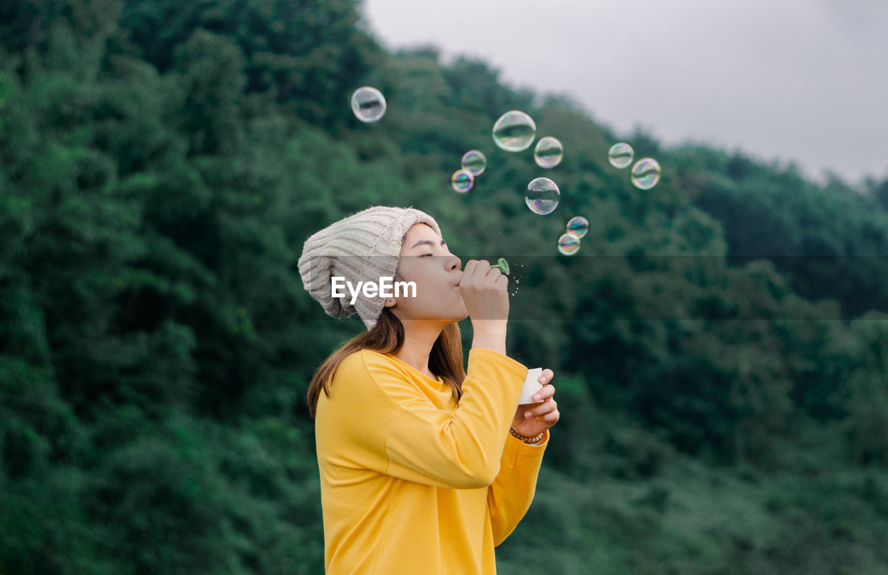 Asian woman blowing bubbles in the park