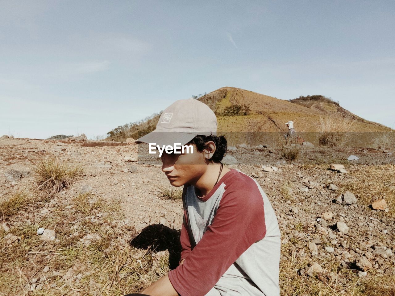 YOUNG MAN STANDING ON LAND AGAINST SKY