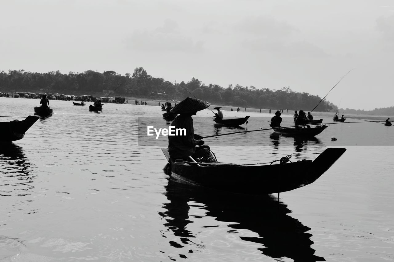 Silhouette men fishing on boat at lake