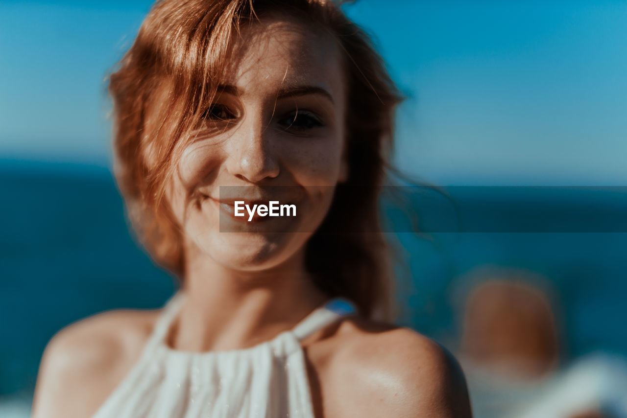 Close-up portrait of young woman against sky