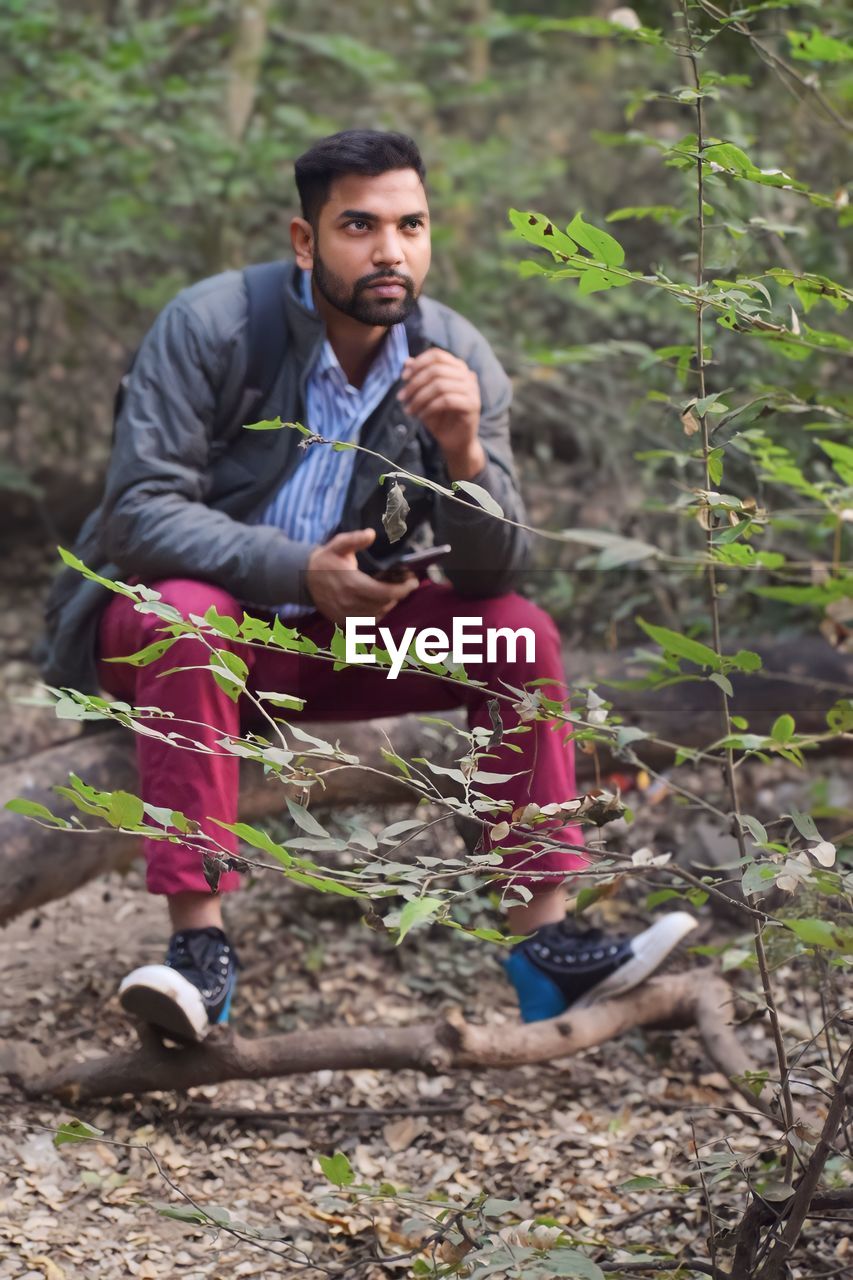 forest, one person, adult, land, leisure activity, full length, tree, activity, nature, lifestyles, plant, soil, men, adventure, sports, young adult, holding, woodland, outdoors, technology, front view, clothing, person, trail, recreation, casual clothing, day, looking, dirt, hiking, equipment, exercising, sports clothing, beard