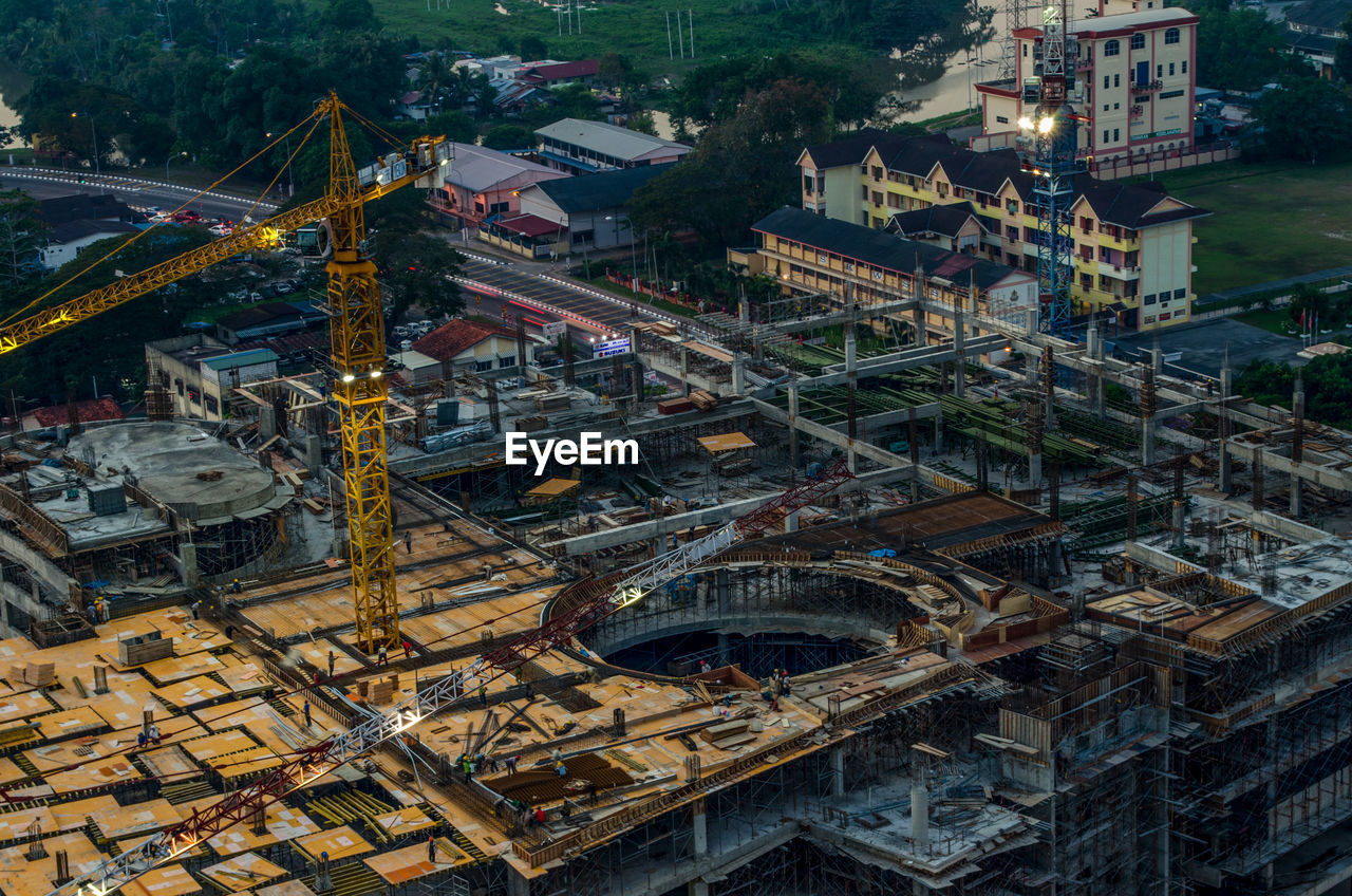 High angle view of crane amidst incomplete building in town