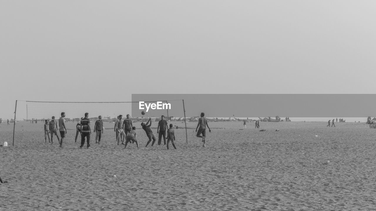 GROUP OF PEOPLE ON BEACH AGAINST SKY