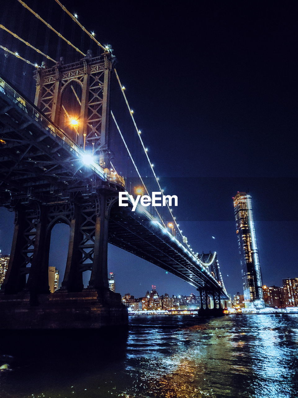 Low angle view of illuminated bridge over river at night