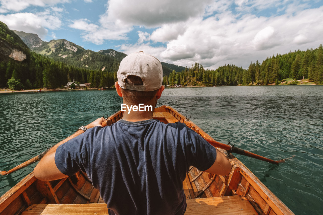 Rear view of man rowing on boat at lake 