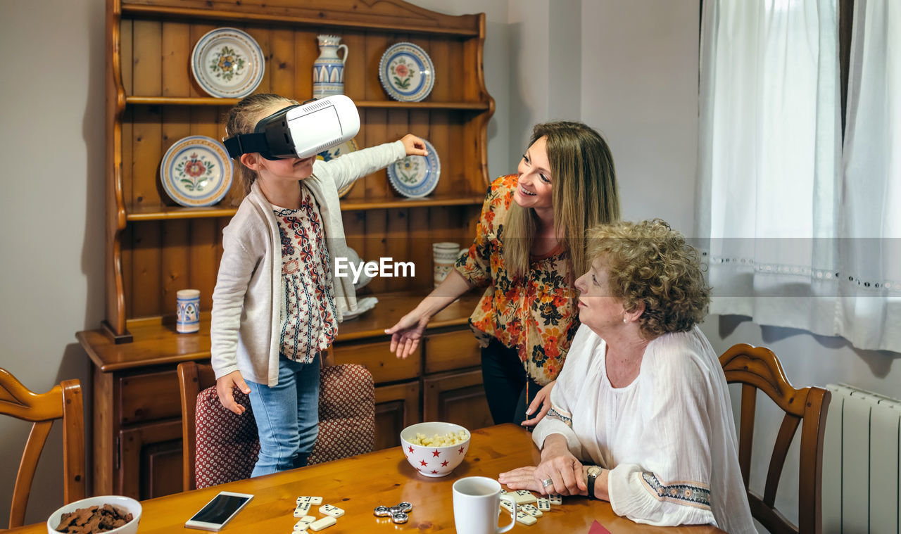 Girl with mother and grandmother wearing virtual reality simulator at home