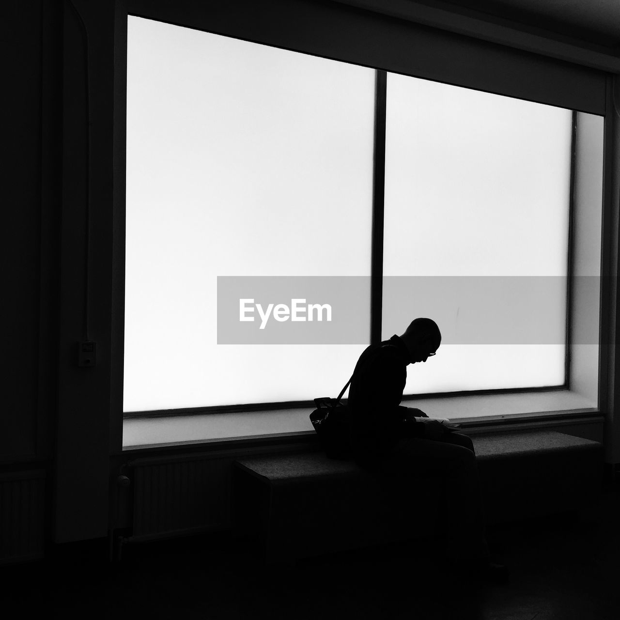 Silhouette man sitting against window
