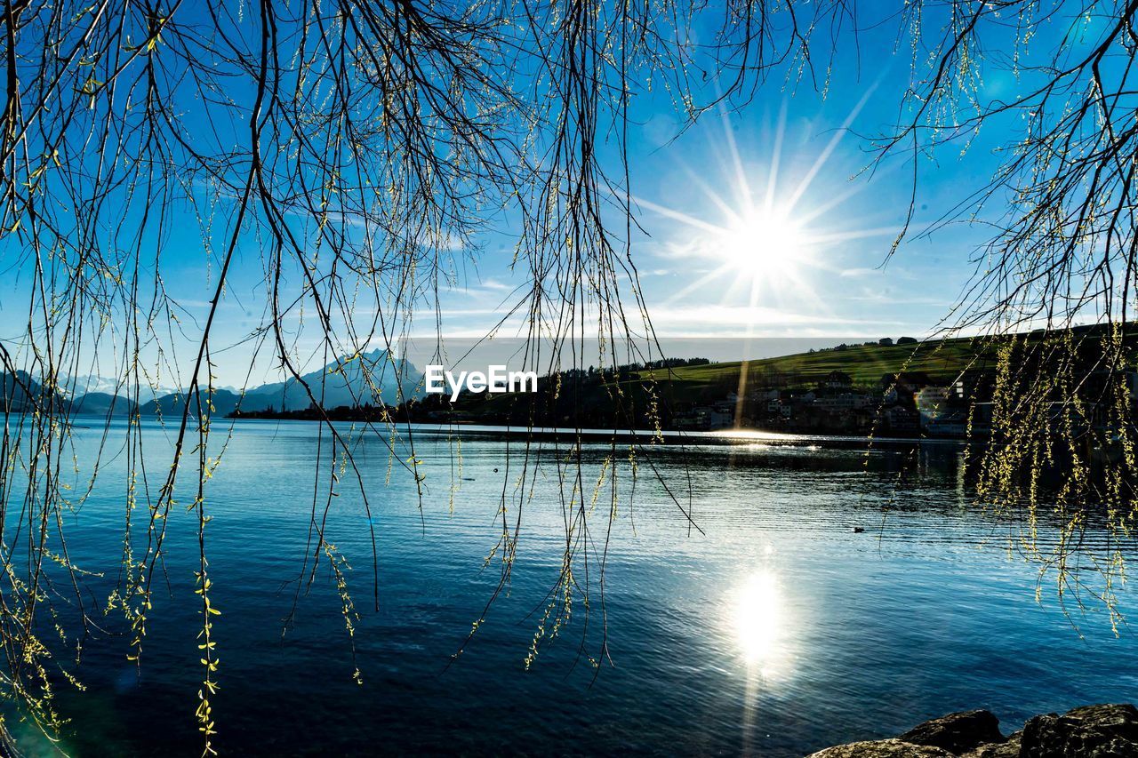 SUN SHINING OVER LAKE AGAINST SKY