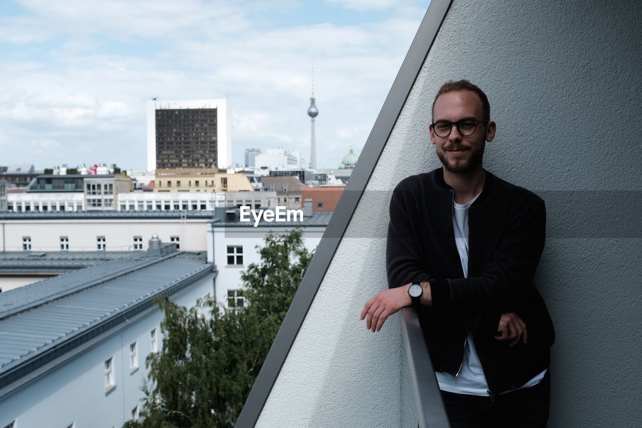 Portrait of young man wearing eyeglasses standing in balcony