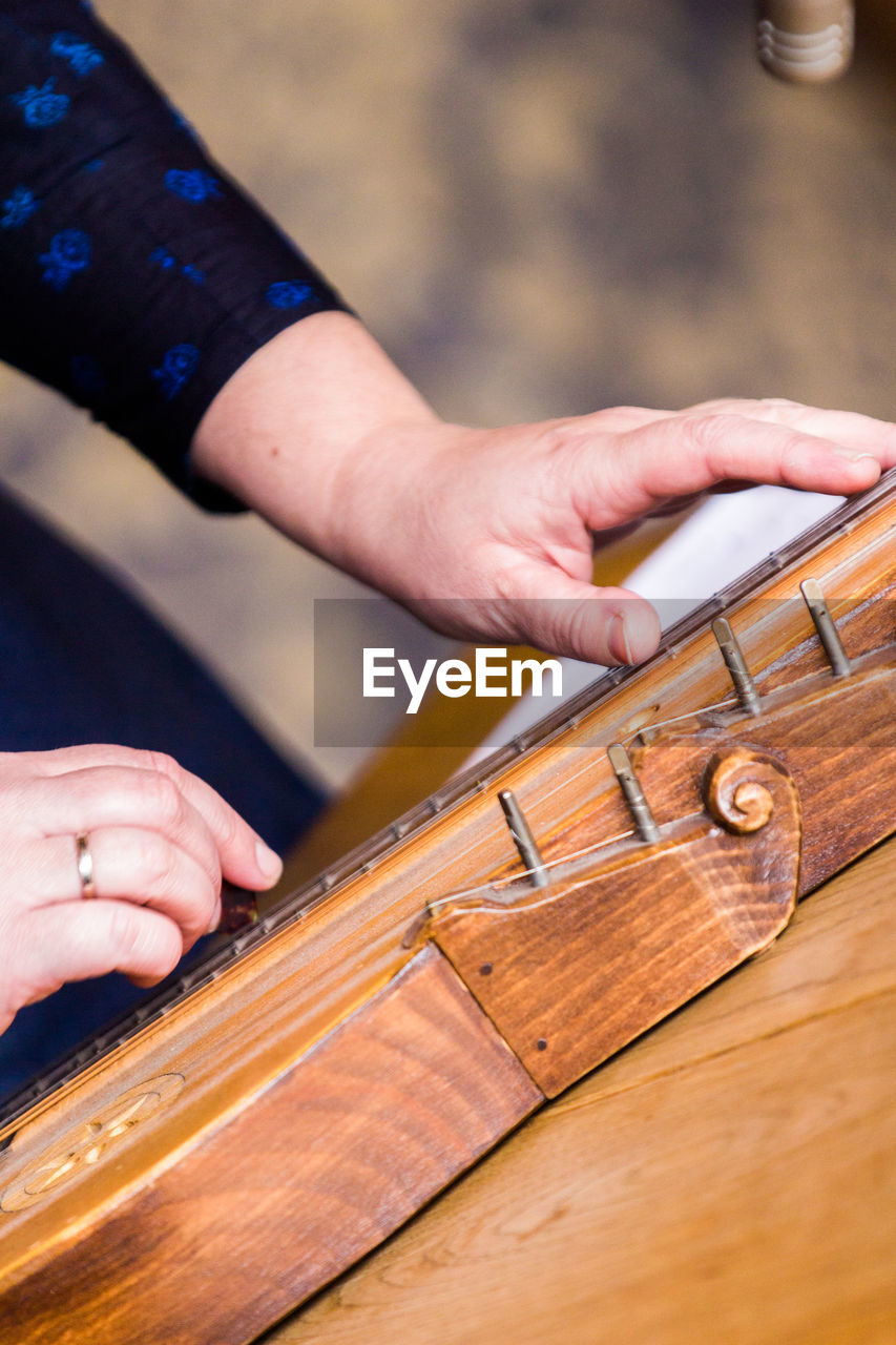 Cropped hands playing zither on table