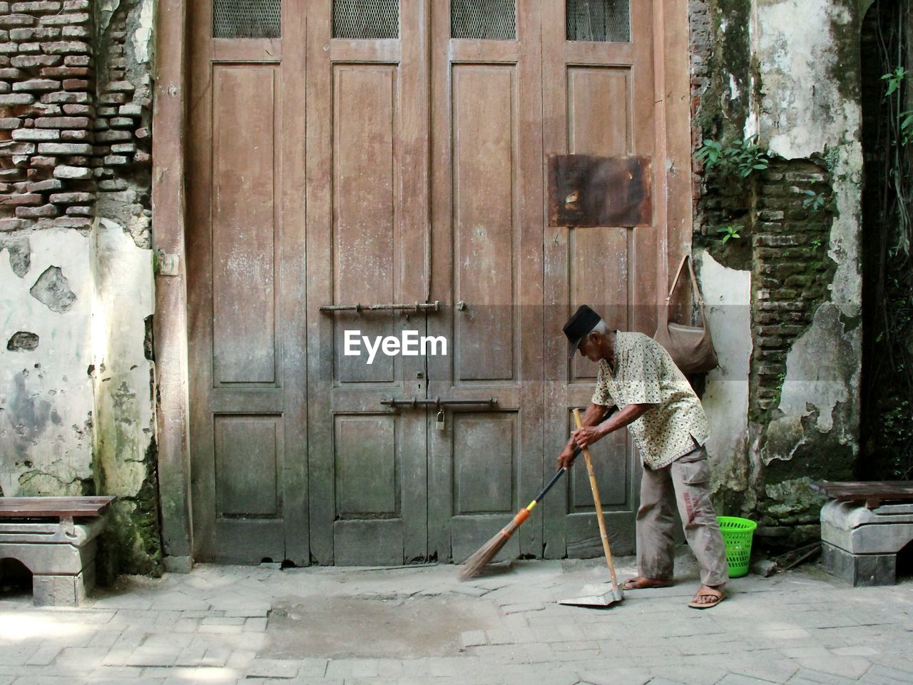 Man sweeping while standing against entrance of building