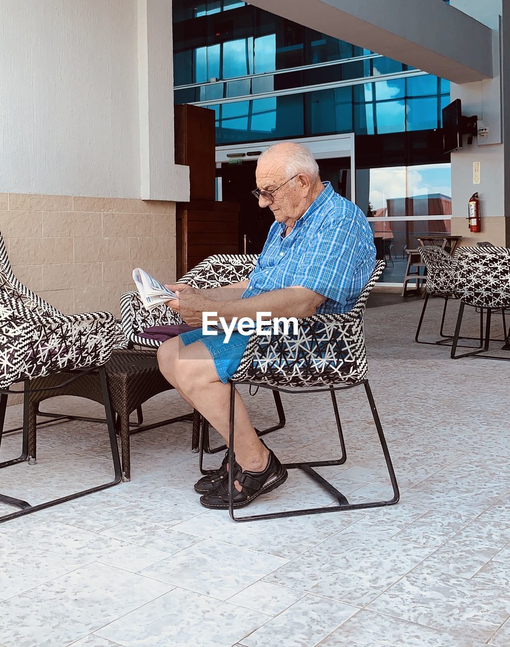 Senior man reading newspaper while sitting on chair