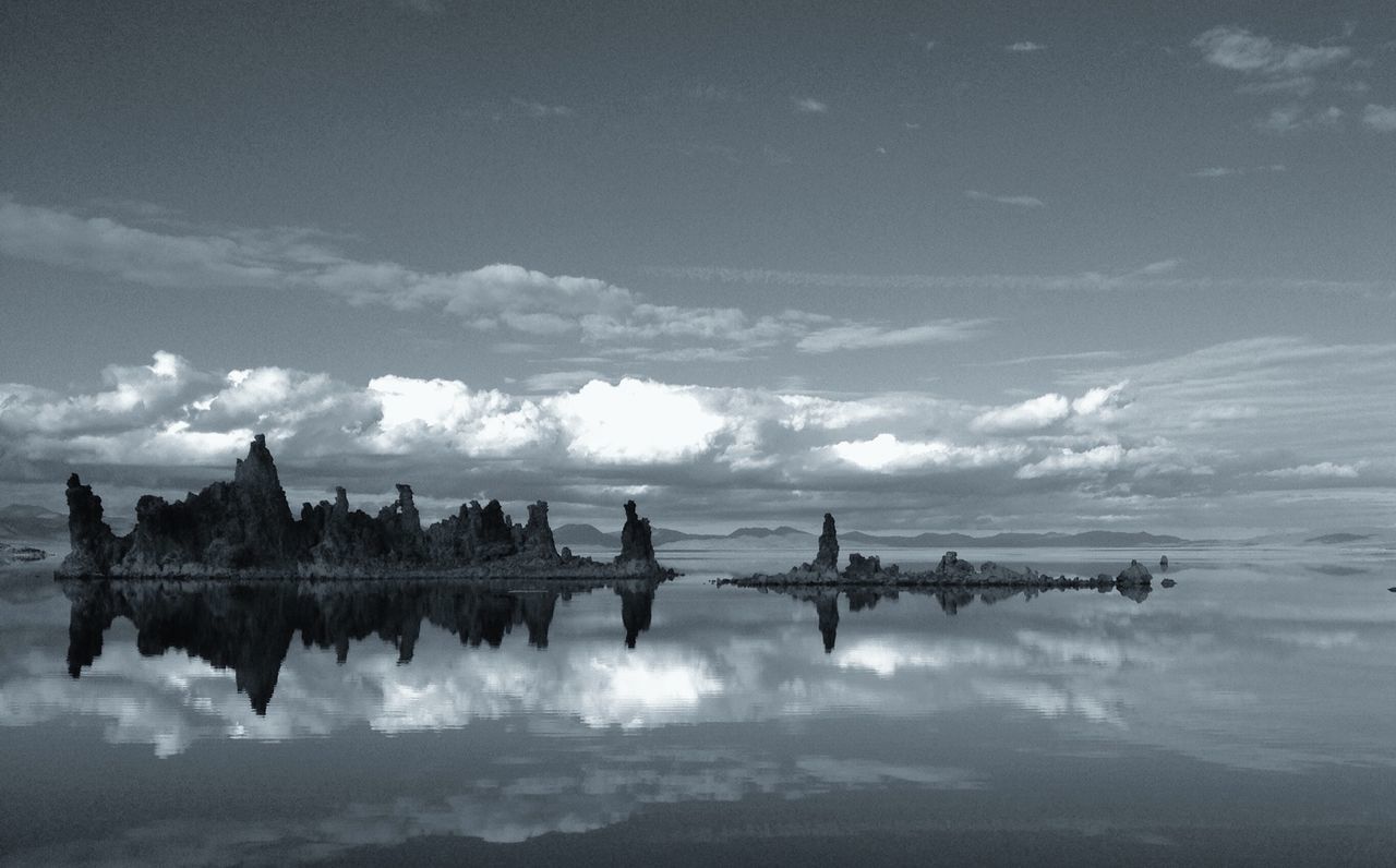Mid distance of tufa outcrops reflected in calm lake against cloudy sky