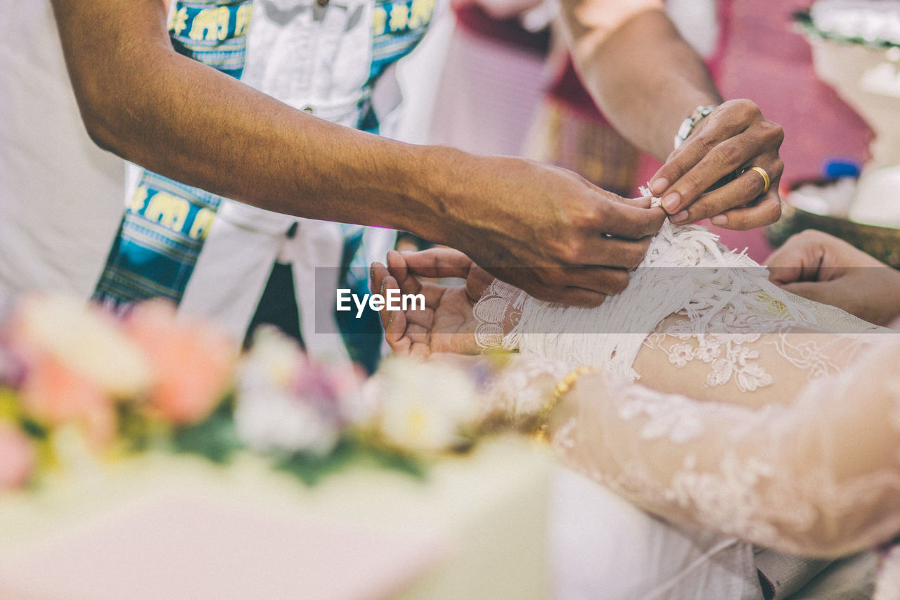 Midsection of woman tying bride wrist