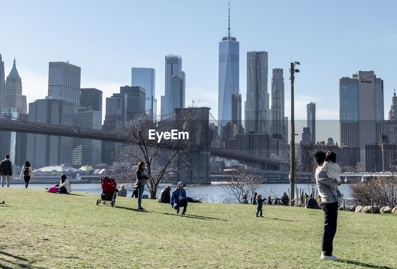 People in park against river and buildings in city