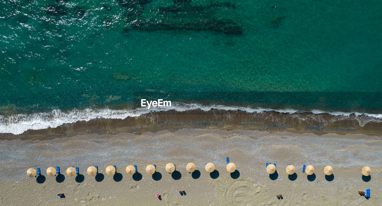 HIGH ANGLE VIEW OF BEACH UMBRELLAS ON SEA