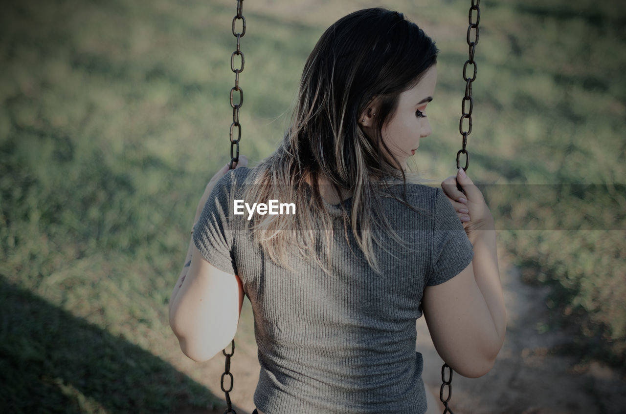 MIDSECTION OF WOMAN HOLDING SWING AT PLAYGROUND