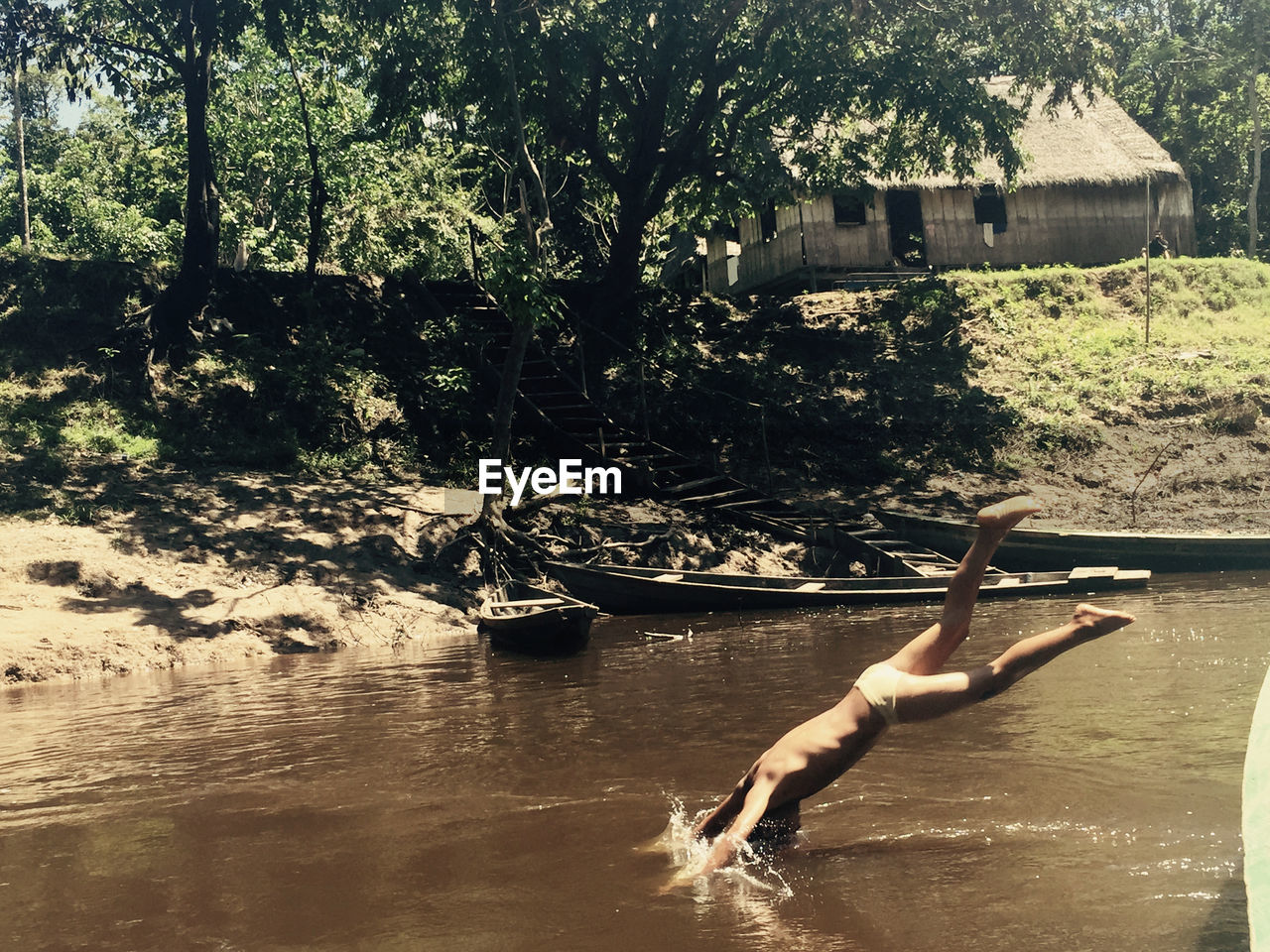 Man diving into water of lake by hut