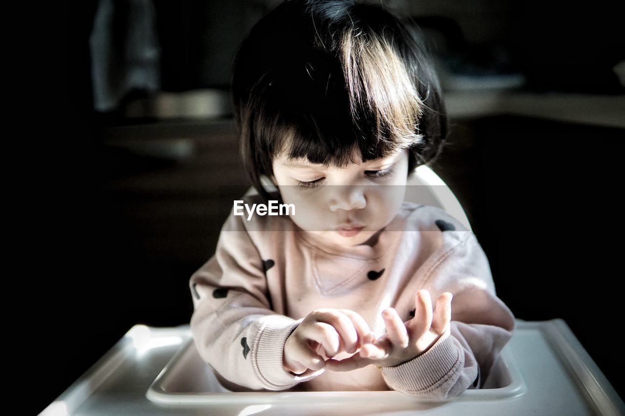 Baby girl sitting on high chair at home