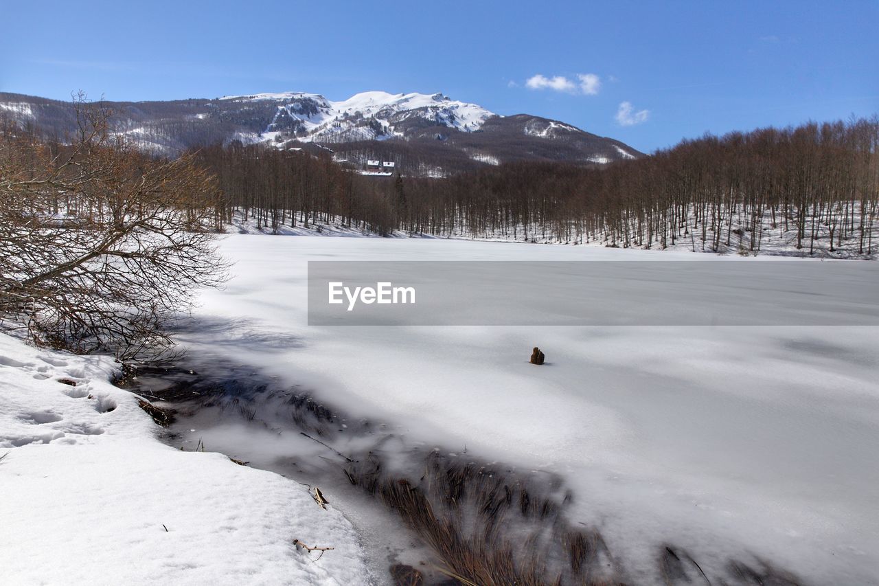 SCENIC VIEW OF SNOW COVERED FIELD BY MOUNTAINS AGAINST SKY