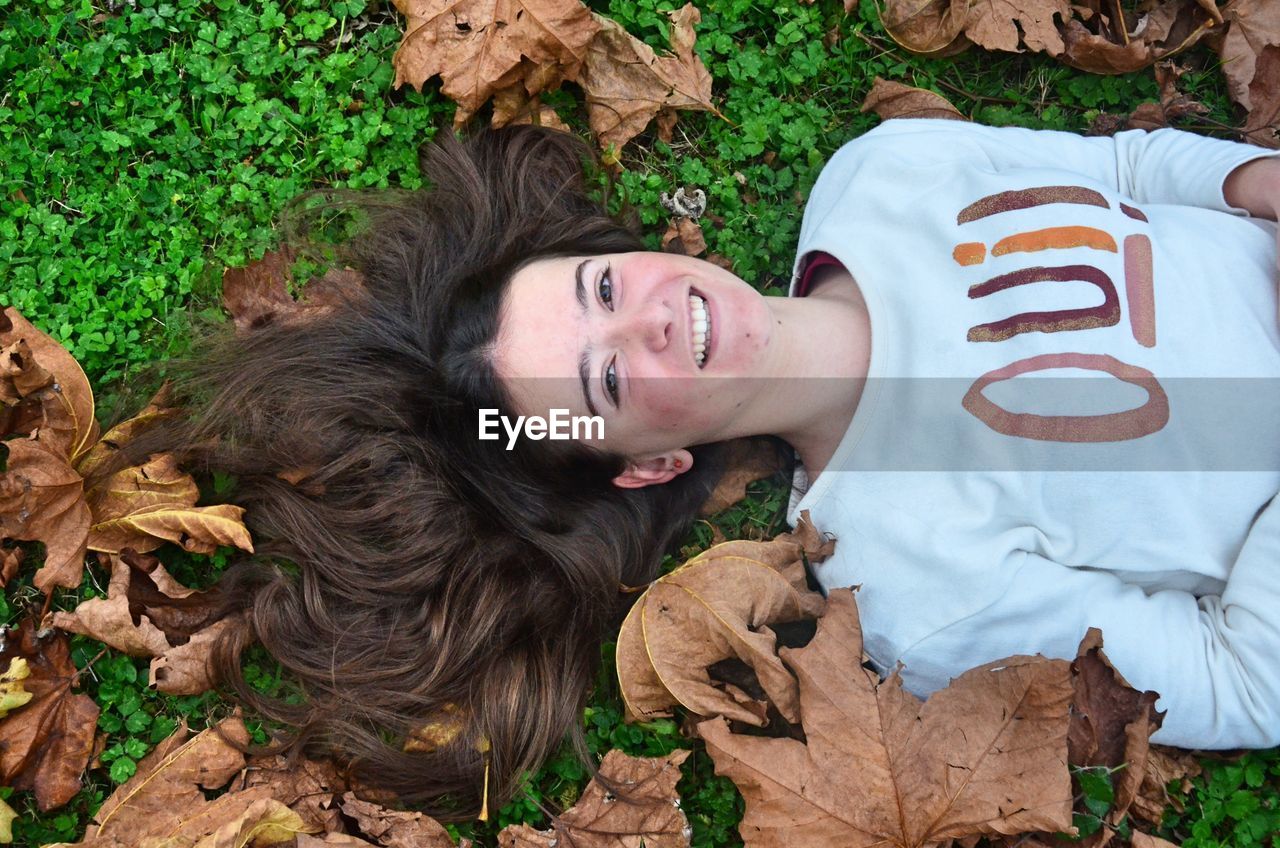 Portrait of happy young woman lying on grassy field