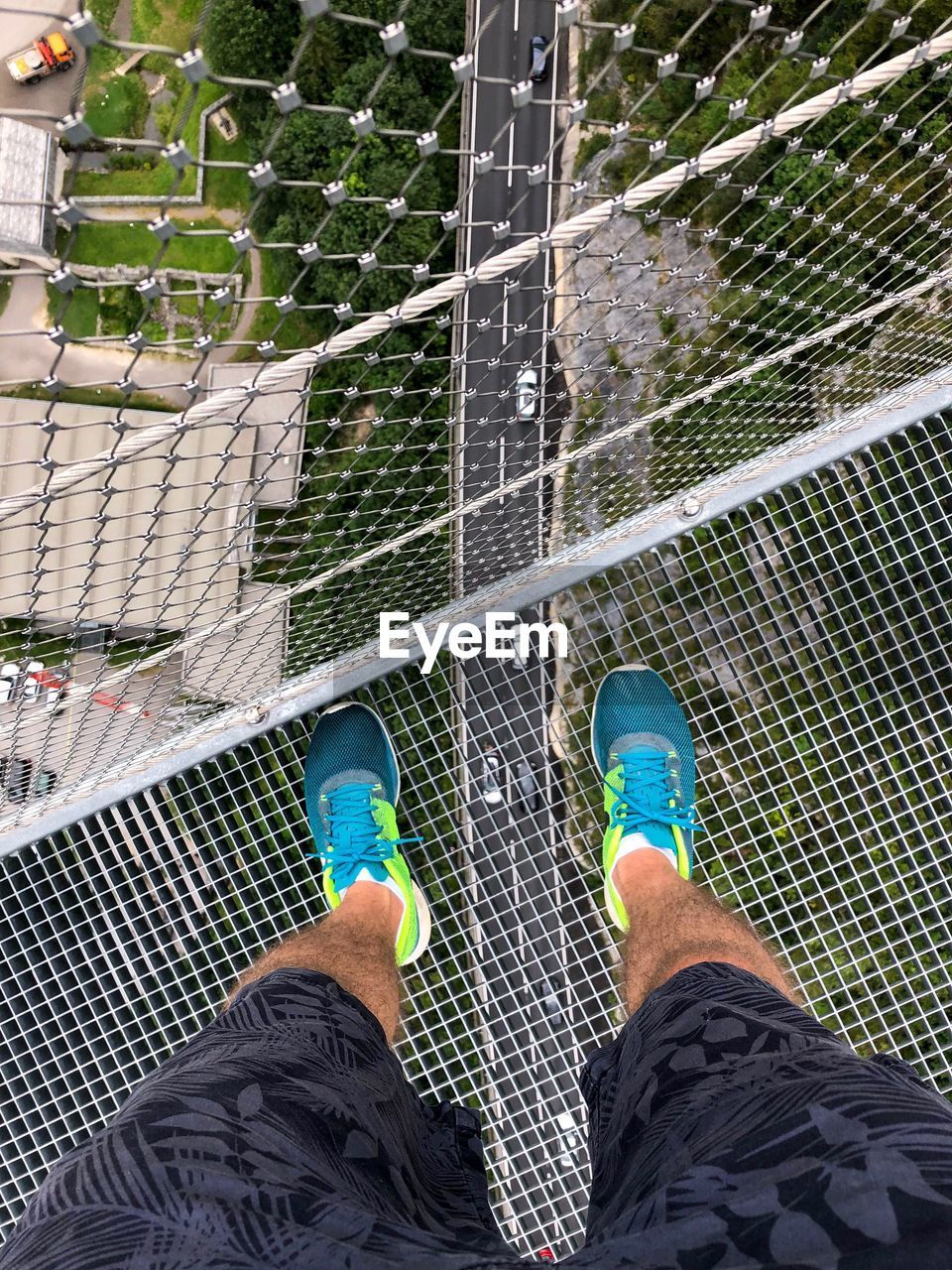 Low section of man standing on metal bridge