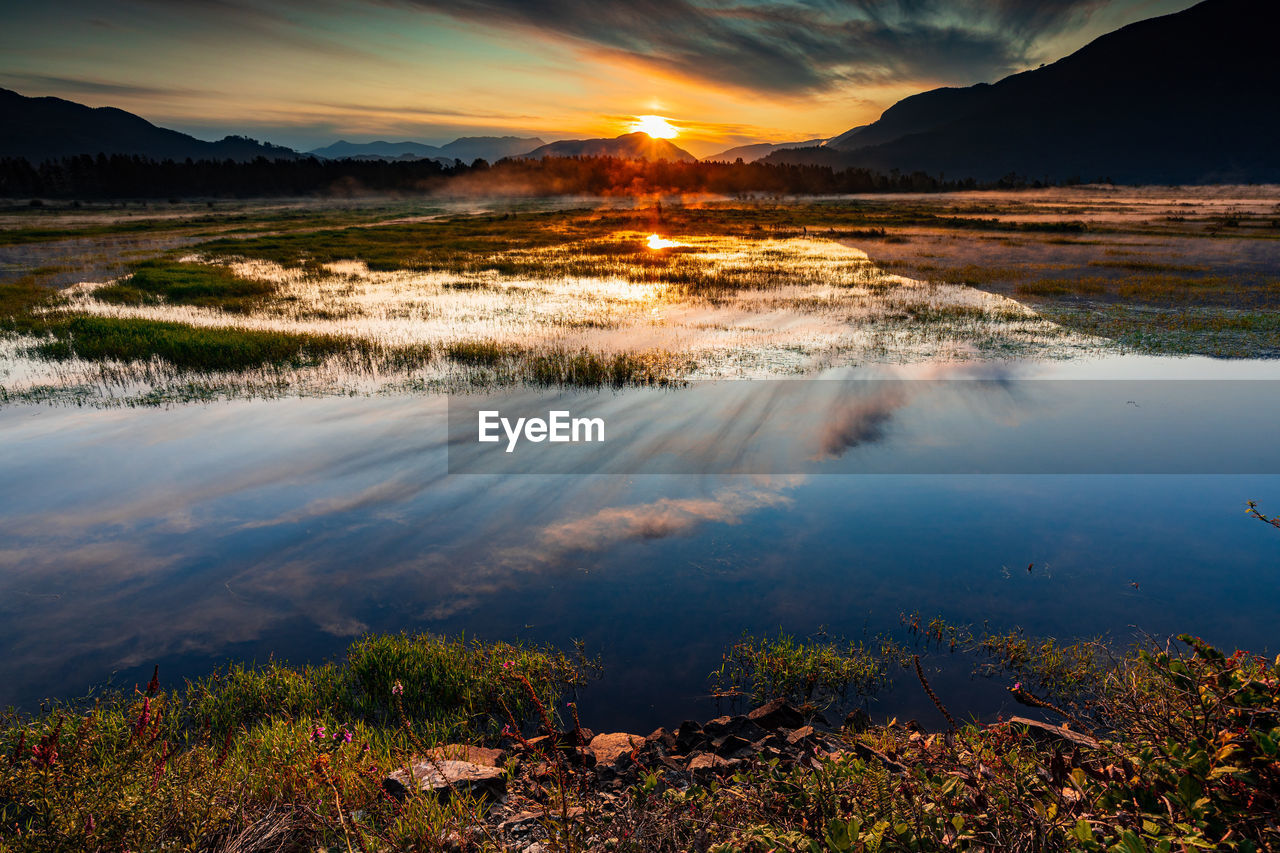 Spectacular sunrise over marshlands with mountain range in background, wonderful reflection