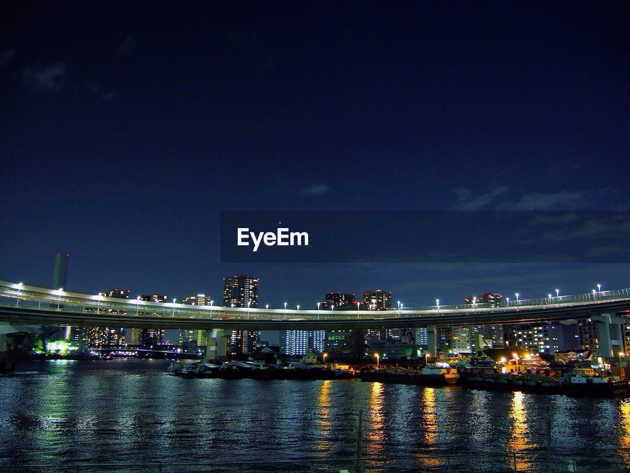 Illuminated bridge over river against sky at night