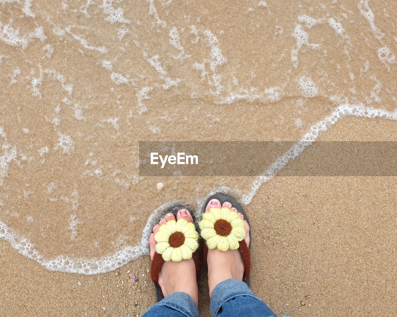 Low section of woman standing on shore at beach