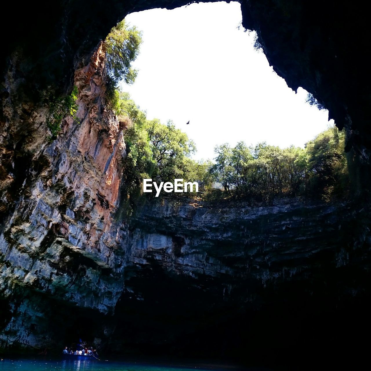 Tourists sailing in boat in sea under cliff