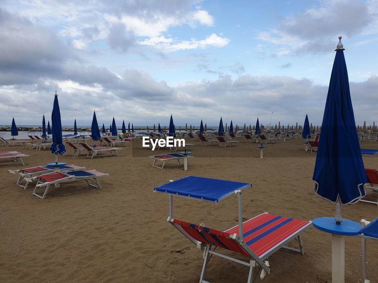 Panoramic view of lounge chairs on beach against sky