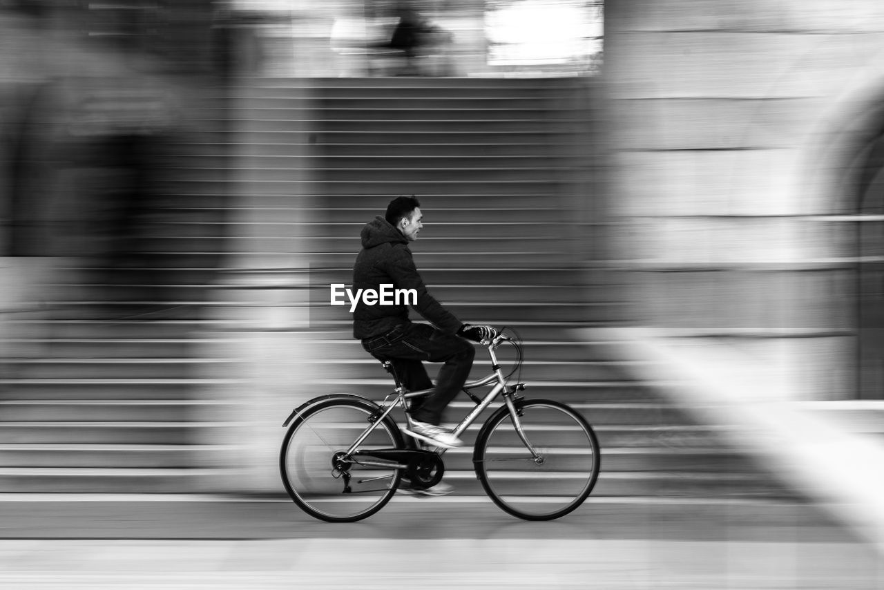 MAN RIDING BICYCLE ON STREET IN CITY