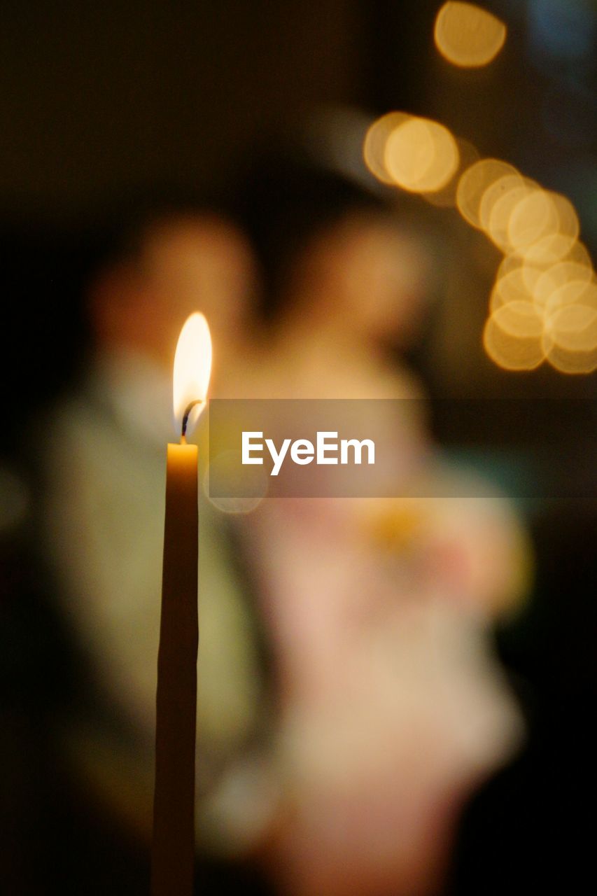 CLOSE-UP OF LIT CANDLE IN THE DARK