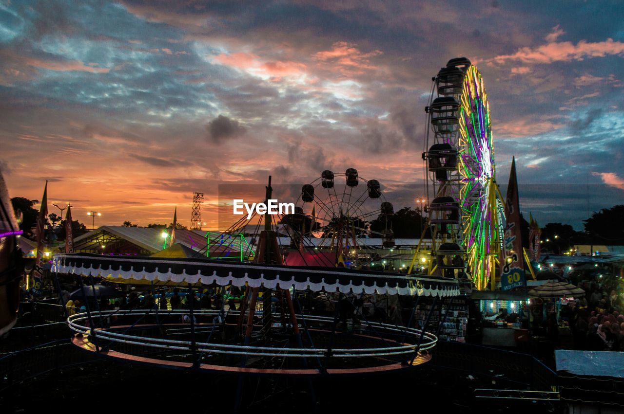 ILLUMINATED FERRIS WHEEL AT NIGHT AGAINST SKY