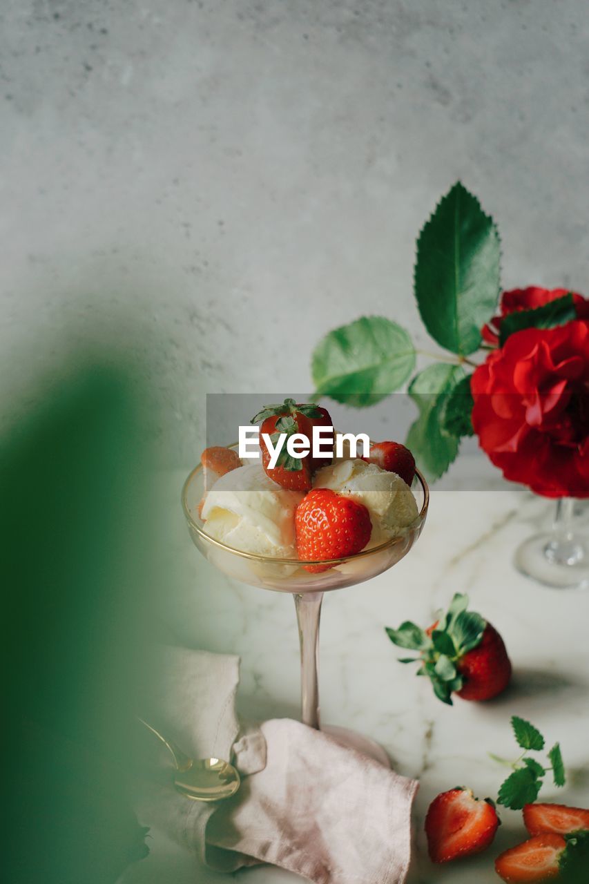 High angel view of vanilla icecream with strawberries in glass on table