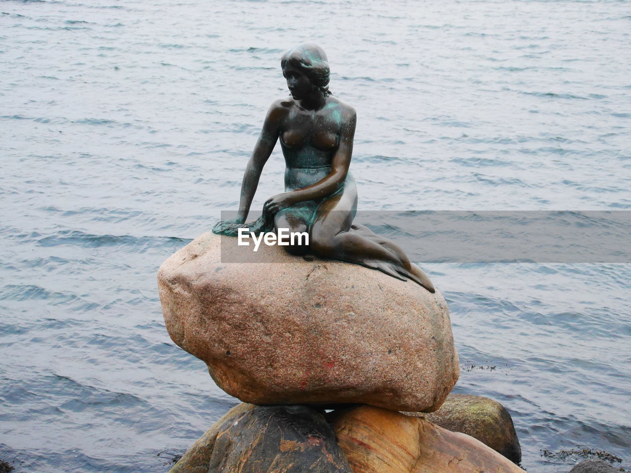 STATUE OF MAN SITTING IN SEA