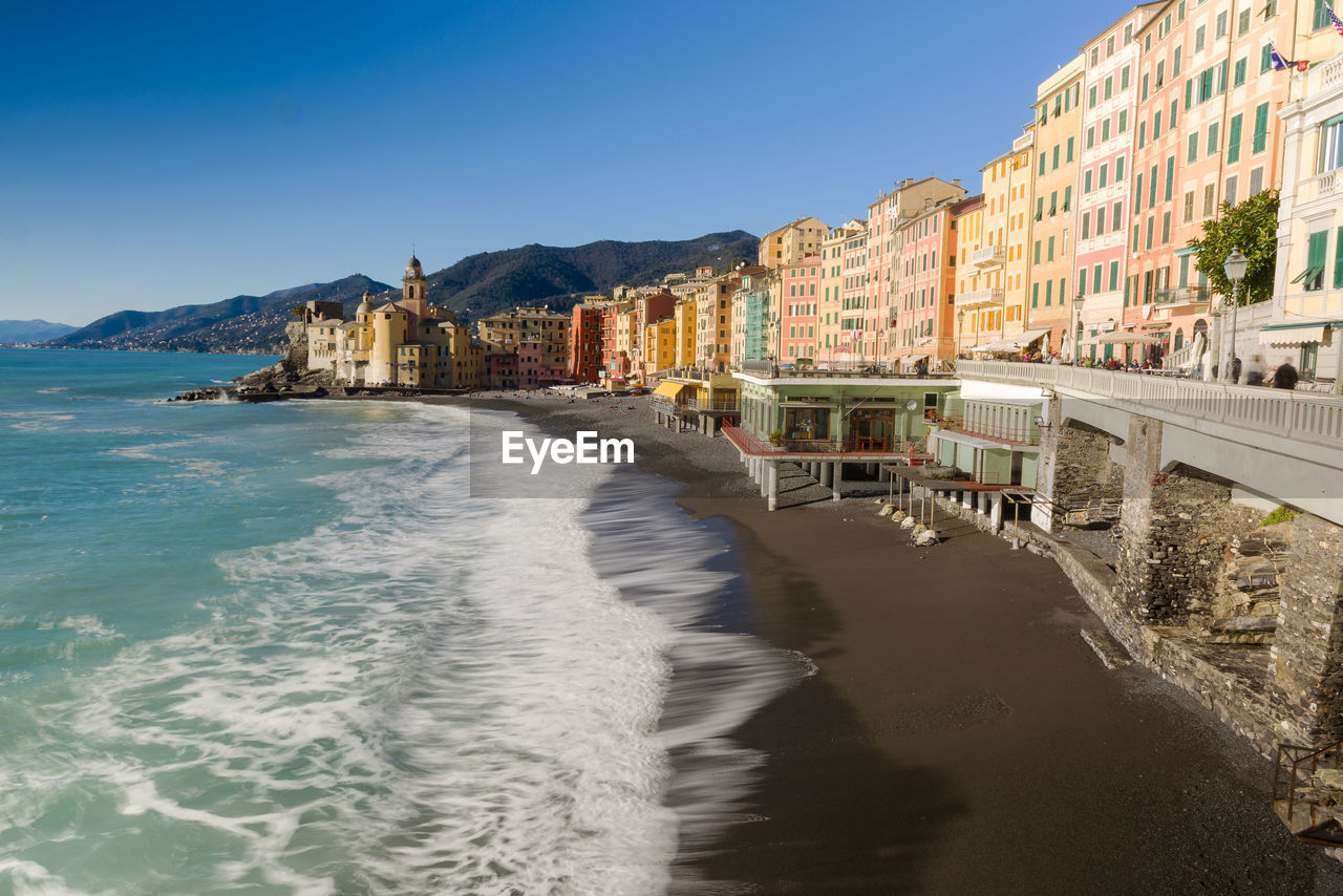 High angle view of beach by buildings against clear blue sky