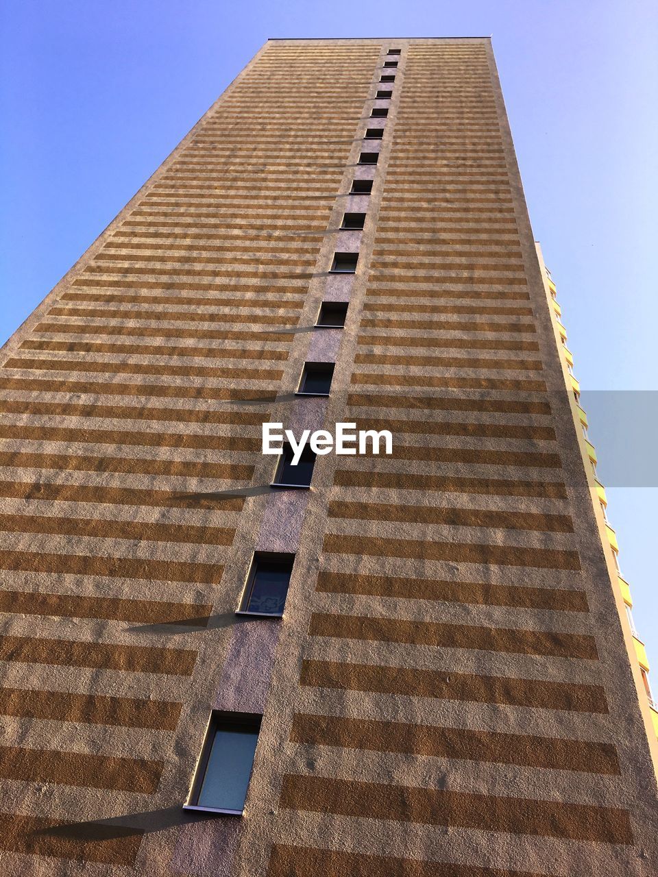 LOW ANGLE VIEW OF TALL BUILDING AGAINST CLEAR BLUE SKY