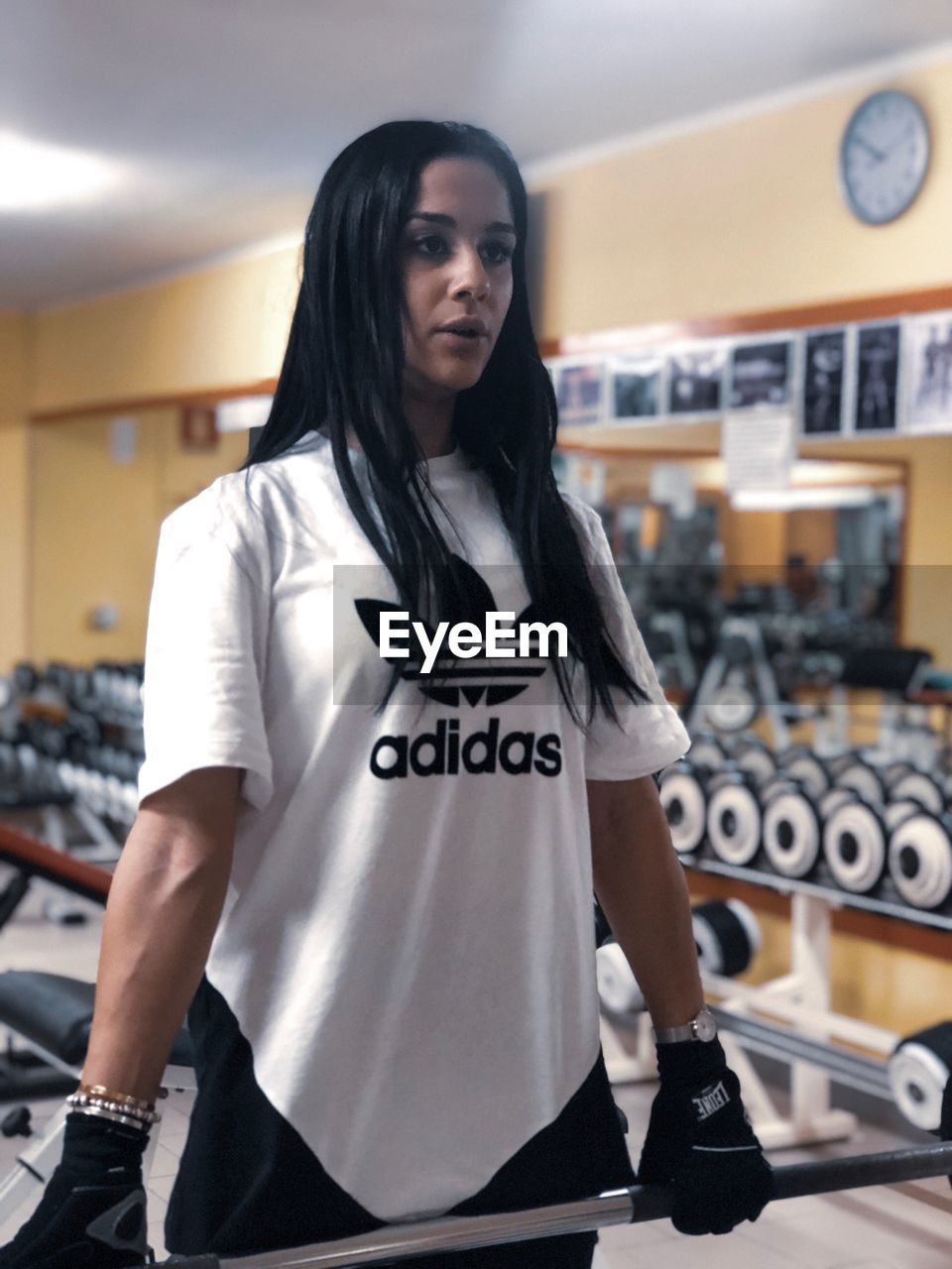 Woman exercising with dumbbell while standing in gym