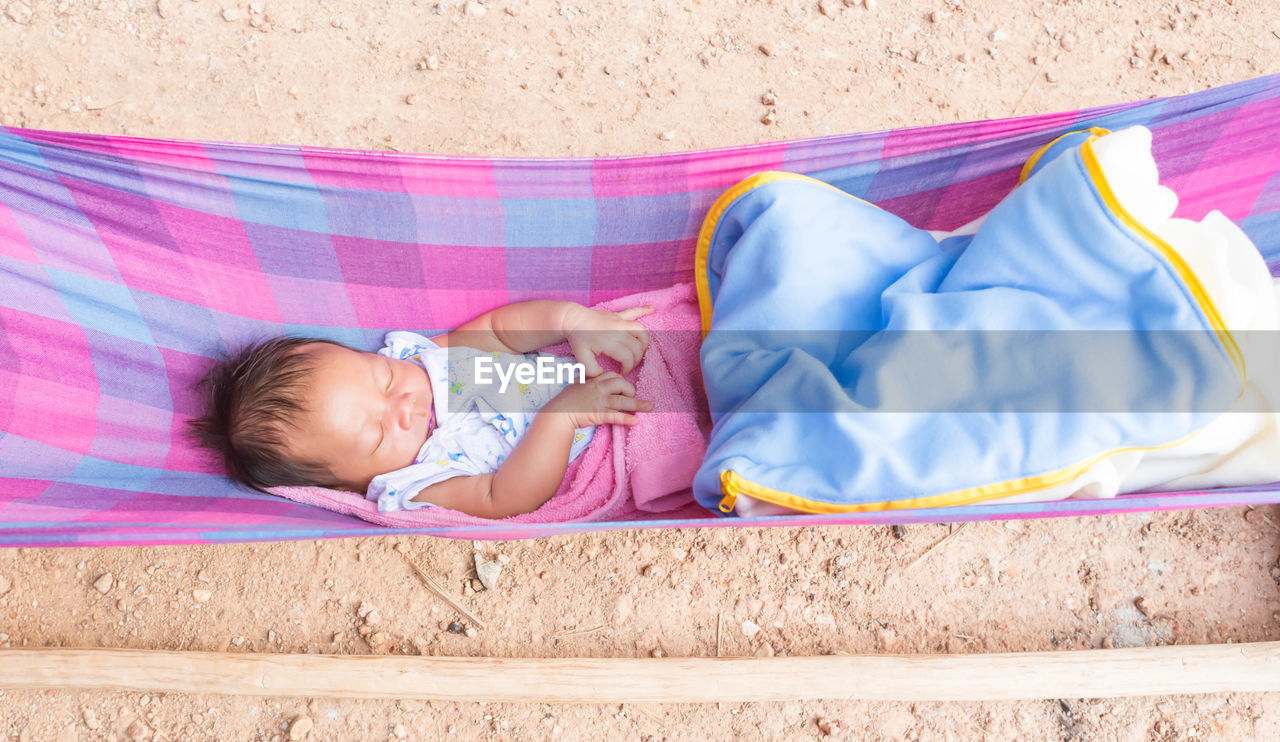 High angle view of cute baby girl sleeping in hammock outdoors