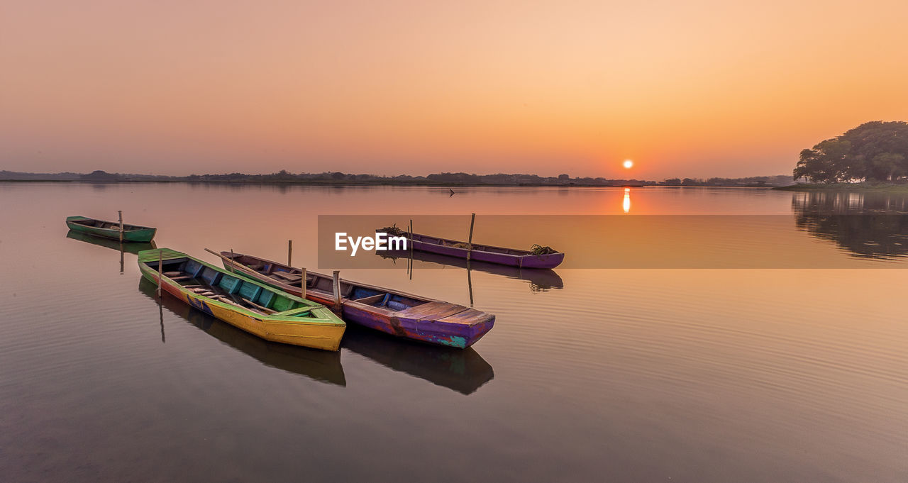 water, reflection, sunset, transportation, nautical vessel, sky, tranquility, nature, mode of transportation, lake, beauty in nature, scenics - nature, tranquil scene, twilight, vehicle, no people, sun, boat, landscape, fishing, dawn, outdoors, travel, environment, multi colored, idyllic, orange color, pier, architecture, travel destinations, moored, beach, sunlight, bay, harbor, silhouette, non-urban scene, clear sky