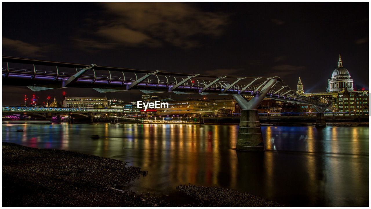 Bridge over river in illuminated city at night
