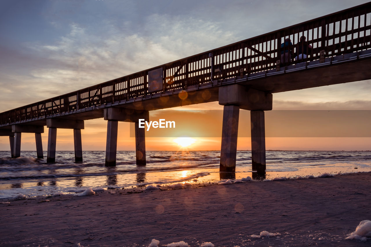 Pier over sea against sky during sunset