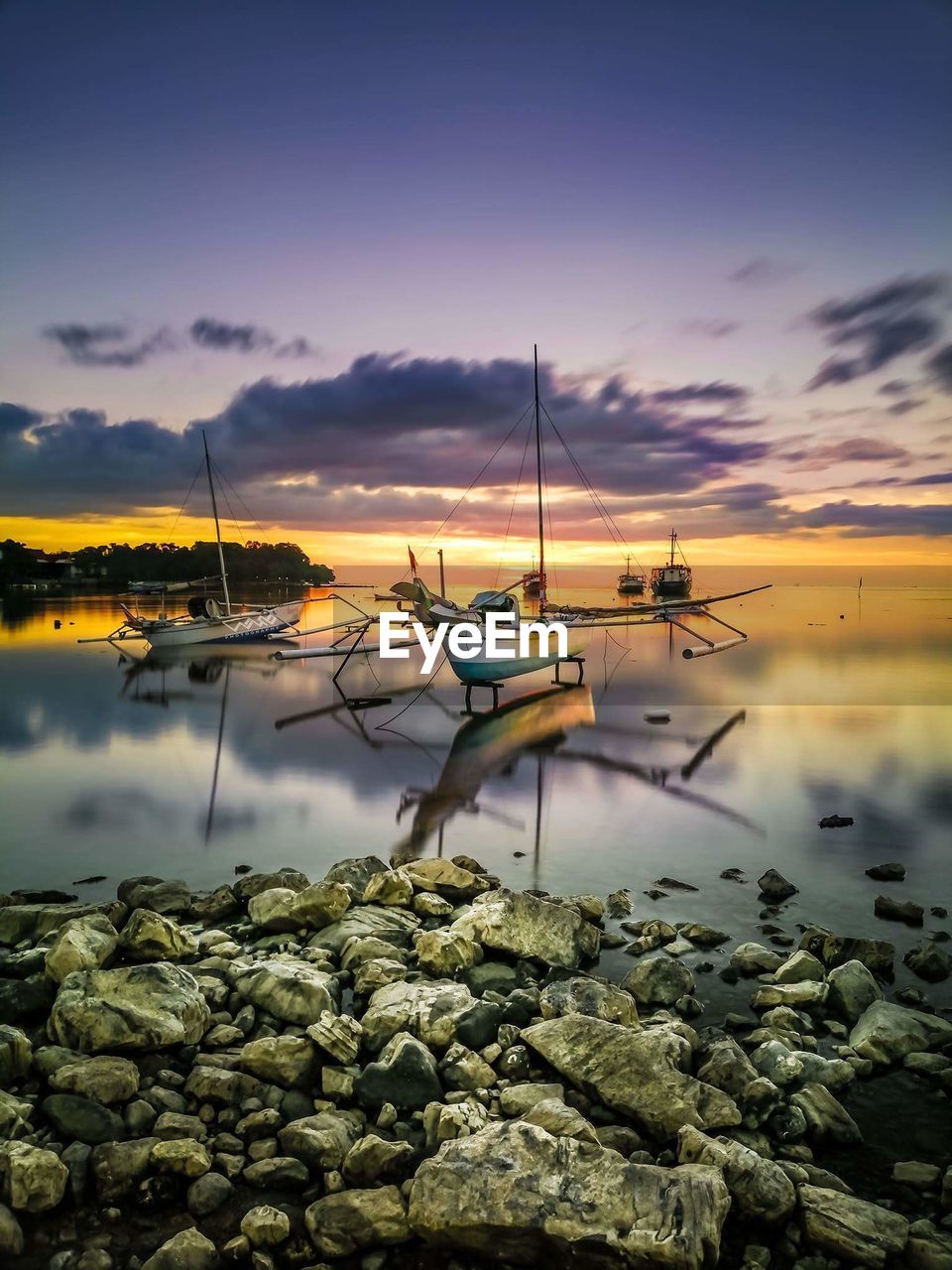 Boats moored on sea against sky during sunset